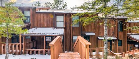 A wooden cabin with a covered porch and a wooden staircase leading to the entrance.