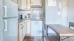 A compact kitchen with white cabinets, a dishwasher, and a coffee maker. - T2 600 m from the beach! Air-conditioned (Le Lavandou)