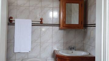 Et badeværelse med toilet, vask og et træskab.