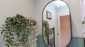 Ein Badezimmer mit einem großen Spiegel, einer Wandpflanze und einer Tür im Hintergrund.