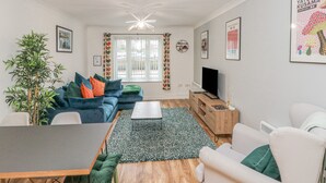 Ein modernes Wohnzimmer mit einer Couch, einem Couchtisch, einem Fernseher und Kunstwerken an den Wänden.
