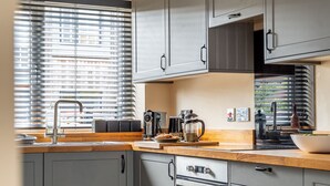 Une cuisine moderne avec des meubles gris, un plan de travail en bois, une machine à café et une bouilloire.