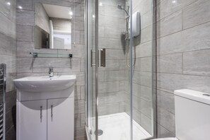 Enjoy a refreshing shower in the sleek bathroom with a glass-enclosed shower and pedestal sink.