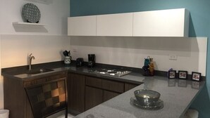 Cozinha moderna com armário de madeira escura, bancada branca e parede azul.
