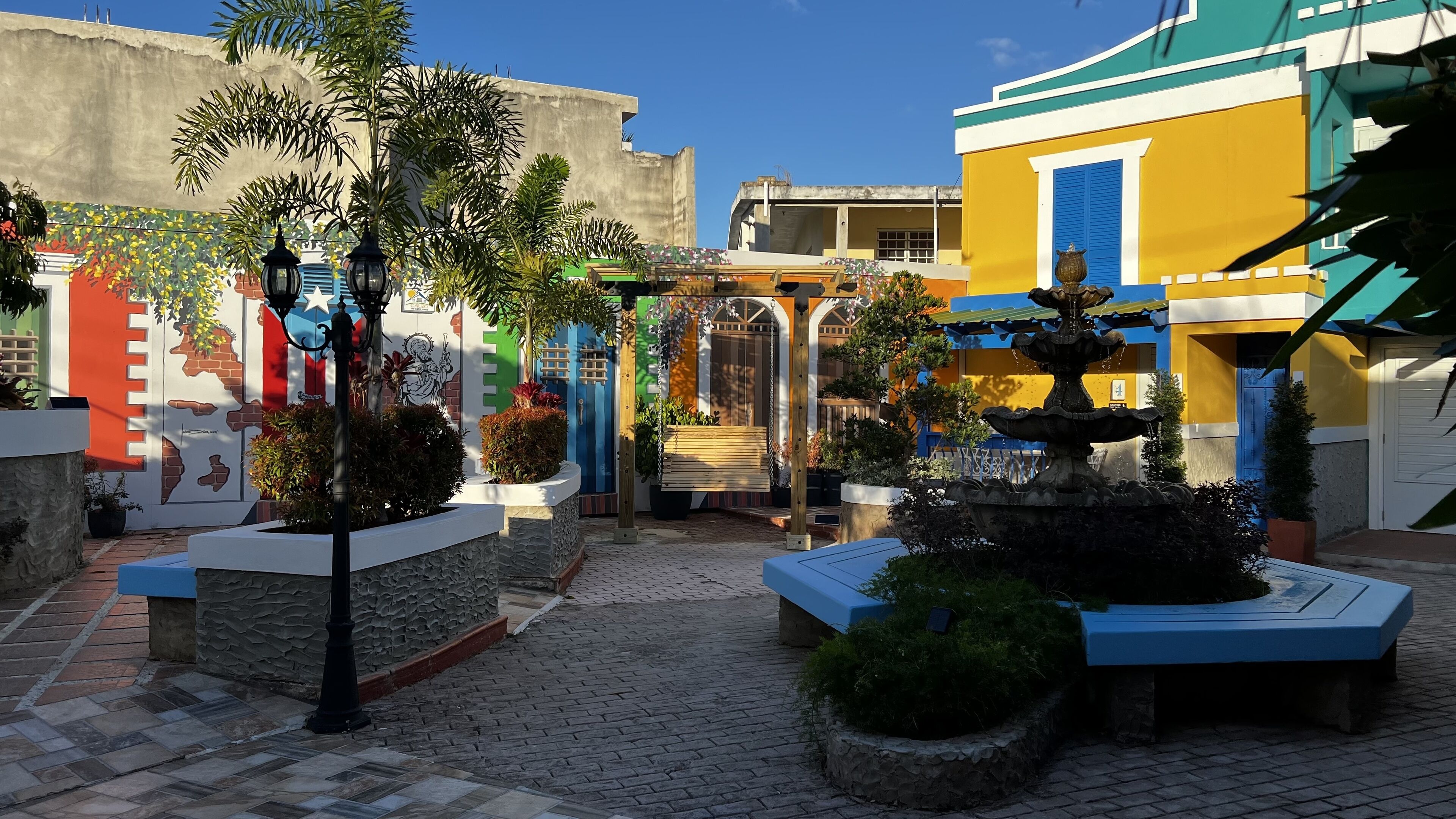 Une cour avec une fontaine, des bancs et une balançoire.