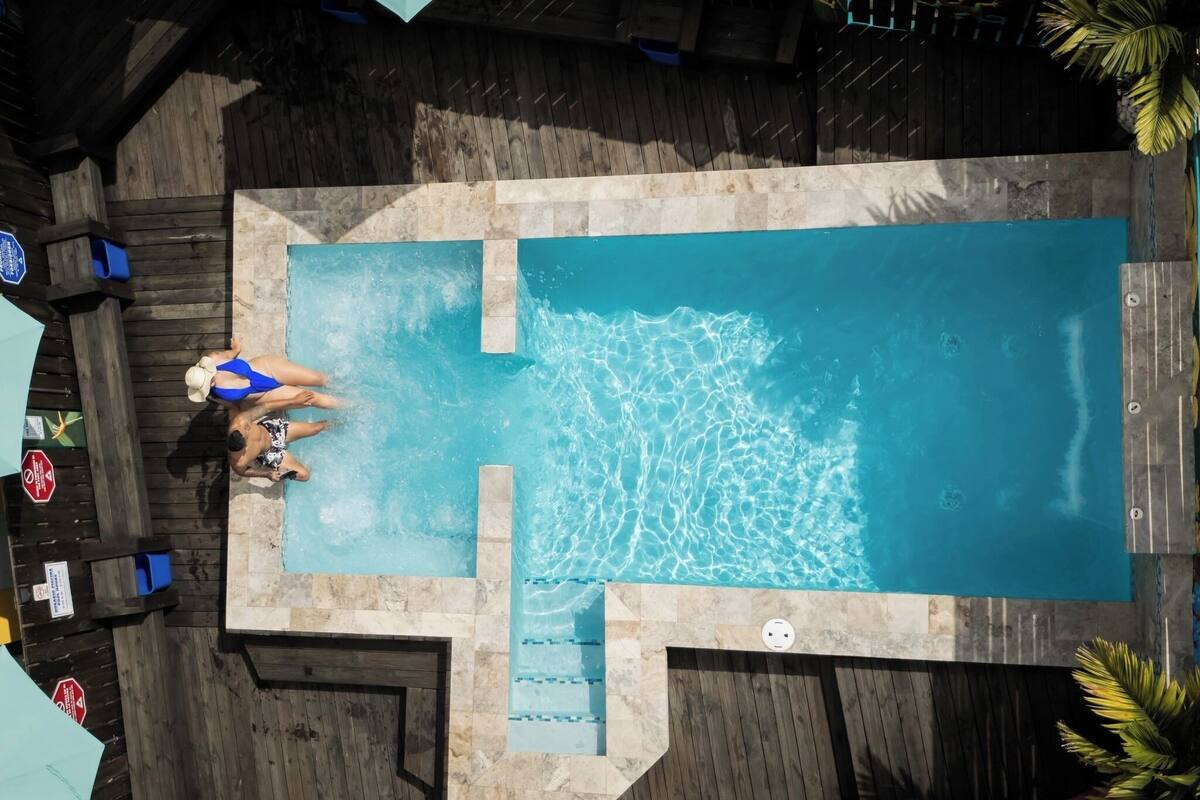 A rectangular swimming pool with a wooden deck surrounding it.