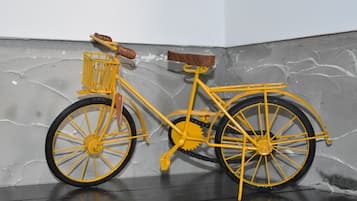 Uma bicicleta amarela com cesto e selim encostada a uma parede texturizada.