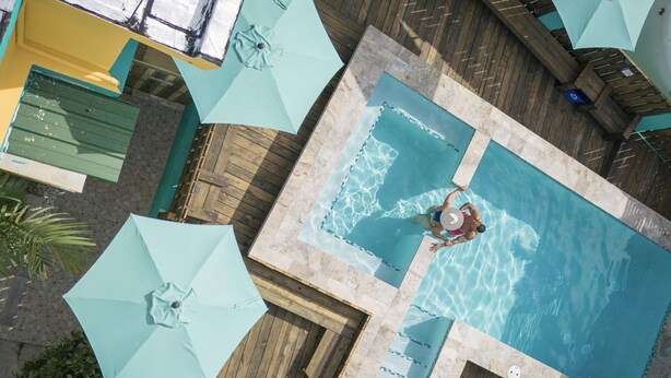 An aerial view of a swimming pool area with multiple umbrellas and lounge chairs. - CALIZO VIP GUEST HOUSE  (Fajardo)