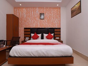 A hotel room with a bed, a nightstand, a chair, a wardrobe, and a painting on the wall.
