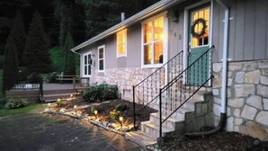 A house with a stone facade, a front porch with steps, and a wreath on the door. - Knotty & Nice Cottage Mountain Views, Near Tail of the Dragon, & Fontana Village (Fontana Dam)