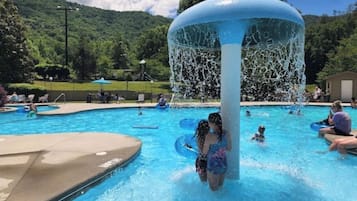 Relax by the pool surrounded by lounge chairs and umbrellas, with a central water feature and a scenic hilly landscape.