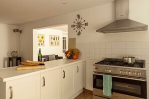 Una cucina con mobili bianchi, un piano cottura in acciaio inossidabile e un orologio a parete.