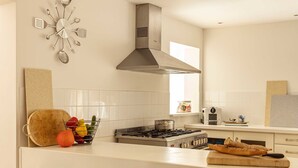 Una cocina moderna con una isla central, taburetes de bar, una estufa a gas y un reloj de pared decorativo.