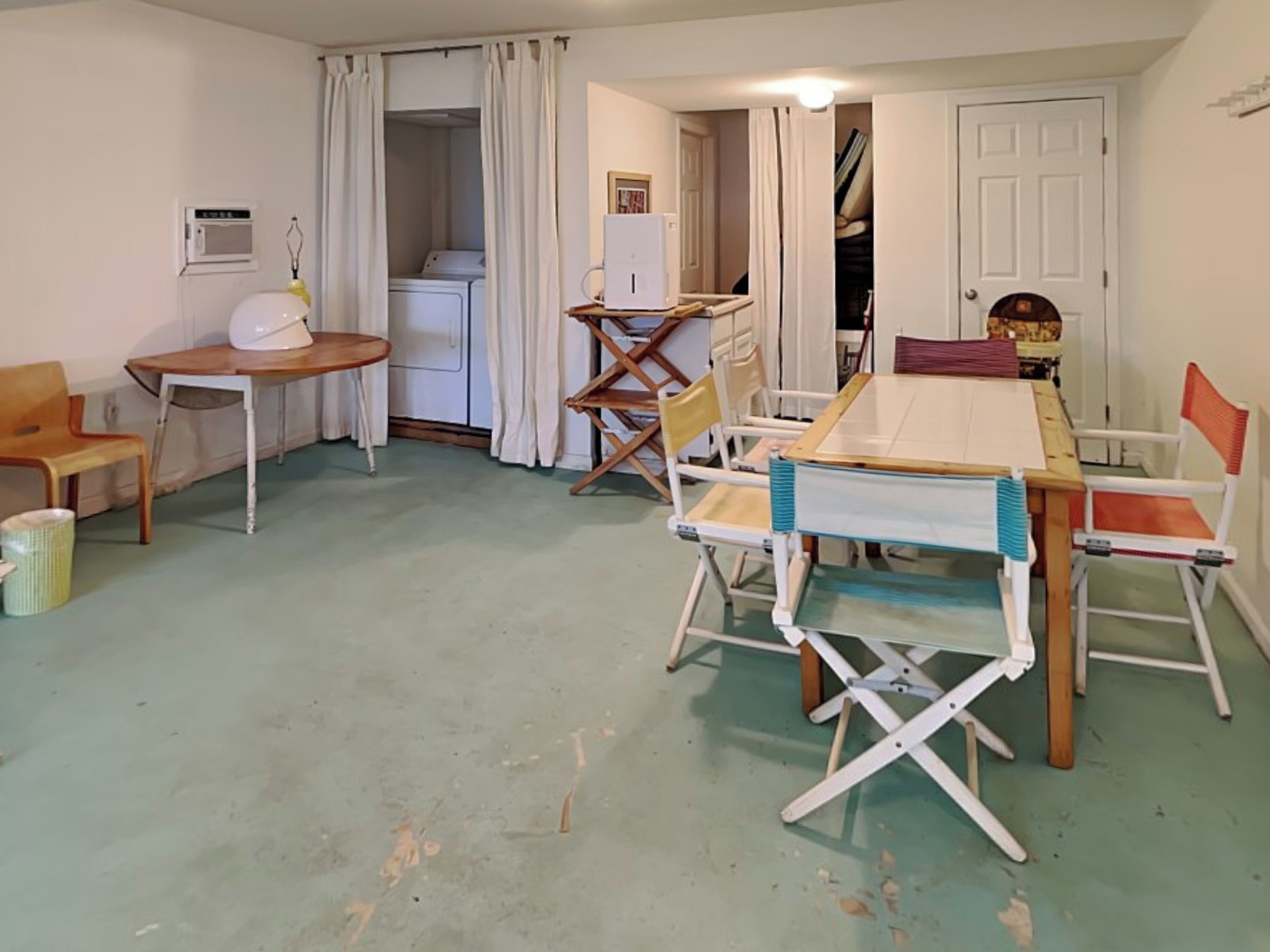 A room with a table and chairs, a washing machine, and a door leading to another room.