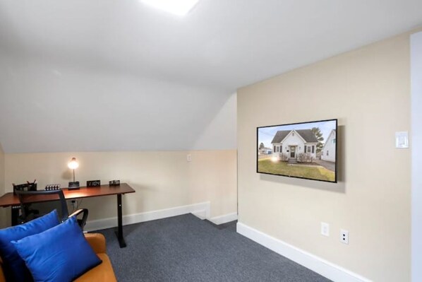 A room with a desk, chair, and a couch. There is a framed picture on the wall. - Patty's Place - Private and Convenient Apartment near Downtown (Frederick)