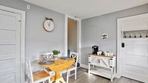 A compact kitchen with a wooden table, white chairs, a coffee station, and a clock on the wall. - Patty's Place - Private and Convenient Apartment near Downtown (Frederick)