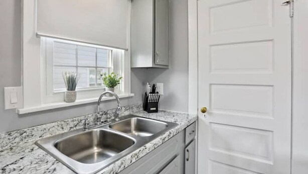 A kitchen with two stainless steel sinks, a window with a plant, and a white door. - Patty's Place - Private and Convenient Apartment near Downtown (Frederick)