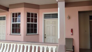 Un bâtiment à la façade rose, aux portes blanches et doté d’un balcon orné d’une balustrade blanche.