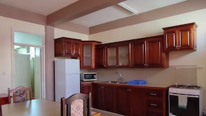 Une cuisine de taille réduite, dotée de meubles en bois, d’un réfrigérateur blanc, d’un four à micro-ondes, d’un évier et d’une cuisinière.