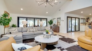 A spacious living room with a large sectional sofa, a round coffee table, and a chandelier.