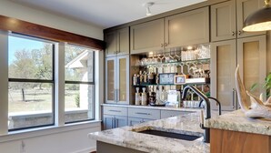 A modern kitchen with a marble countertop, built-in cabinets, and a glass display shelf.