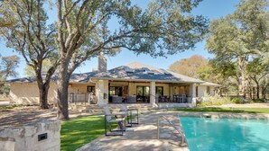 A house with a swimming pool, patio with chairs, and a covered outdoor area with tables and chairs.