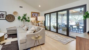 A modern living room with a grey sofa, a small round table, and a large window with a view of the outdoors.