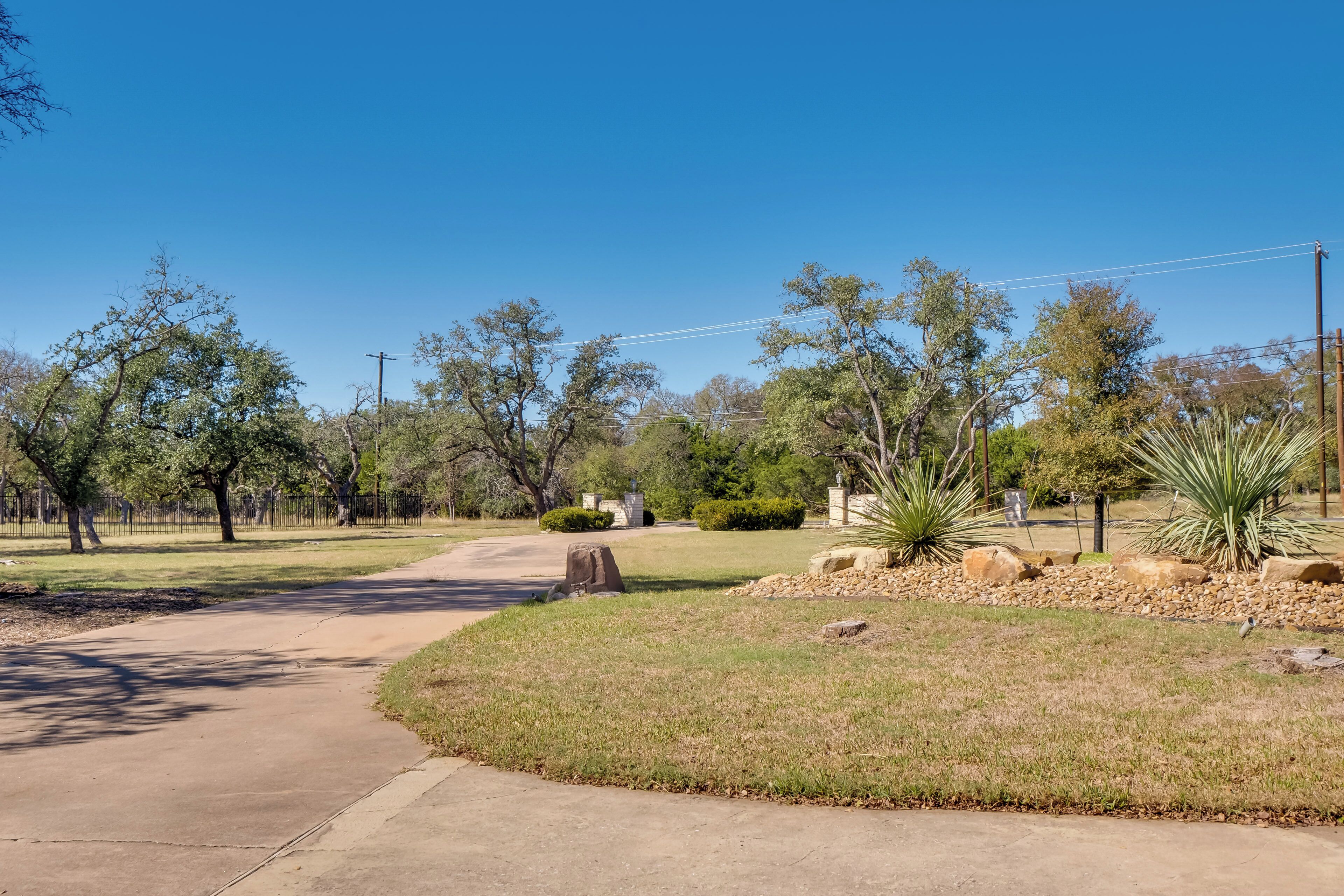 A paved pathway curving through a landscaped area with trees and shrubs.