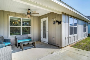 A covered porch with wicker furniture, a ceiling fan, and a door with a metal grill. - Foley Vacation Rental: 7 Mi to Gulf Shores Beaches (Foley)