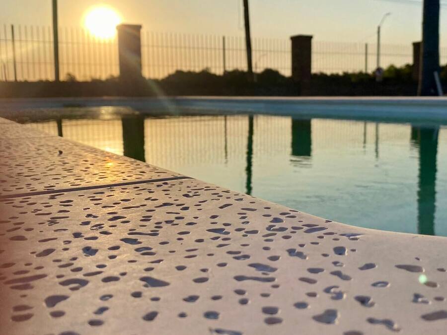 Zona de piscina con suelo de metal y vista despejada del atardecer al fondo.