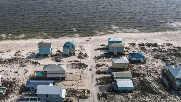Eine Küstenlandschaft mit mehreren Gebäuden, von denen einige blaue Dächer haben, in der Nähe eines Sandstrandes und des Ozeans.