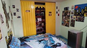 Een slaapkamer met een bed, een garderobe en verschillende posters aan de muur.
