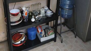 A kitchen area with a black shelf holding various kitchen items, a kettle, a blender, and a water dispenser.
