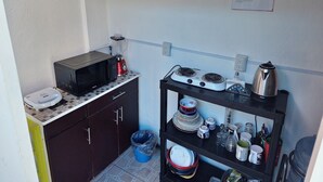 Una cocina compacta equipada con microondas, licuadora, cocina a gas y distintos utensilios de cocina.