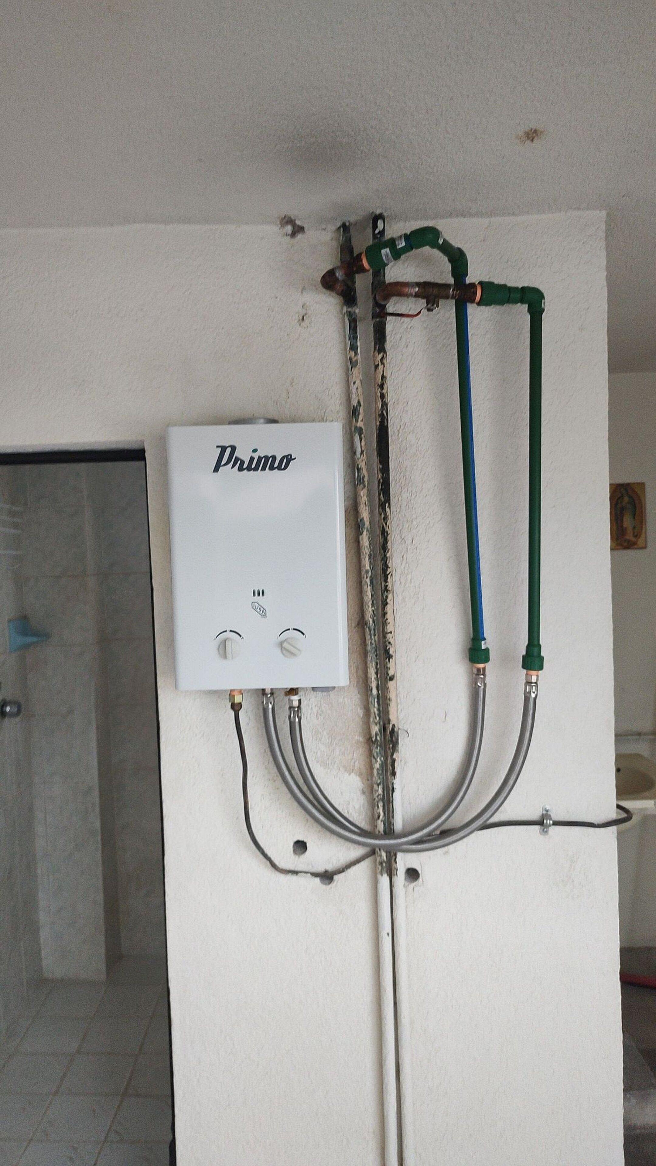 A white wall with a white electrical box labeled "Primo" and multiple pipes connected to it.