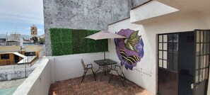 Relax on the charming balcony with a table for two, a vibrant mural, and a large umbrella for shade.
