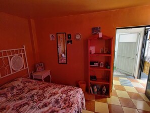 Cozy retreat with a bed, bedside table, and mirror, plus a door leading to an outdoor area.