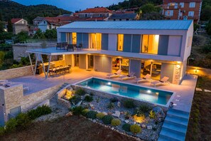 A modern two-story house with a swimming pool, outdoor seating, and a well-lit patio area. - Villa Hypnotic with Pool (Žman)