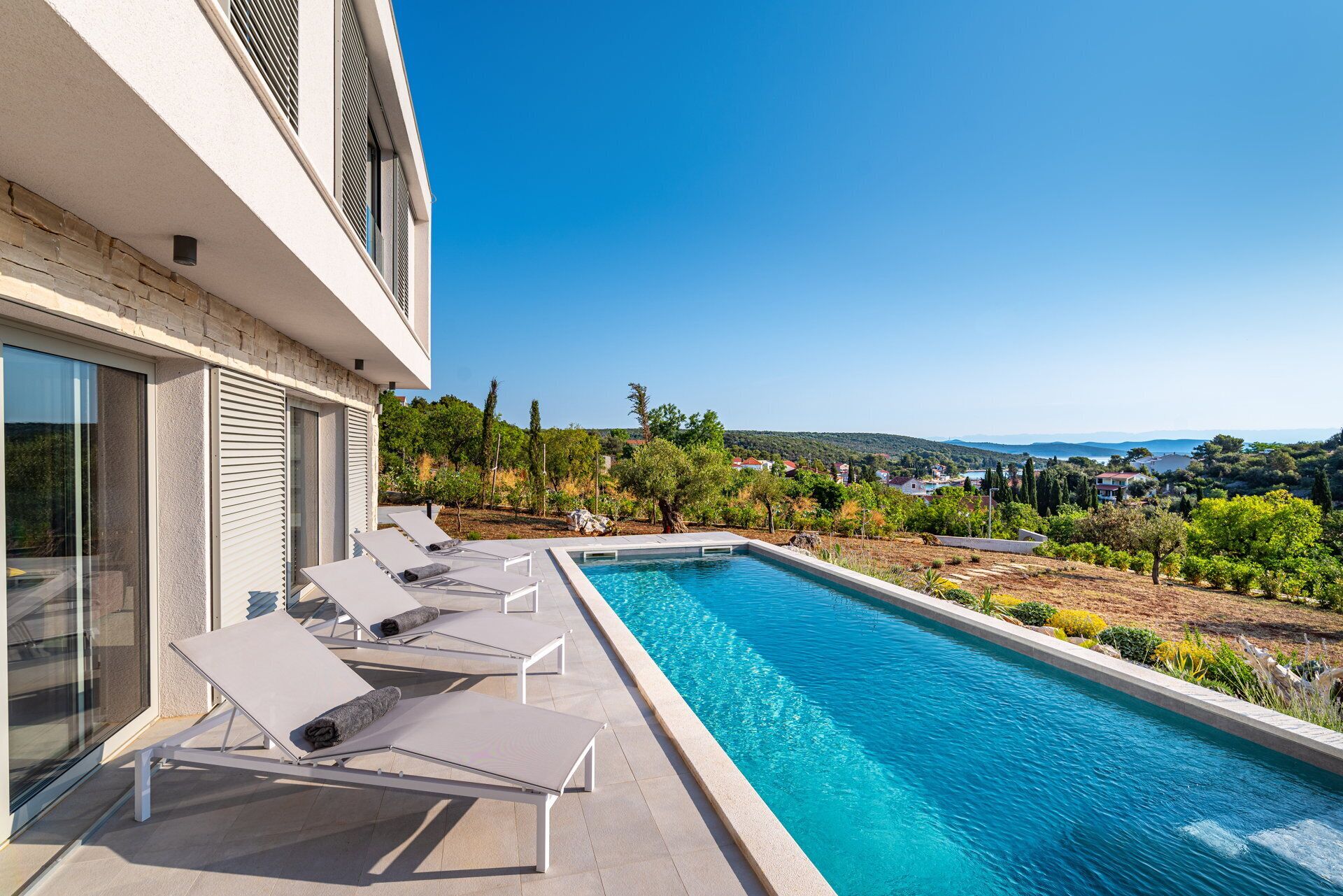 A modern poolside area with lounge chairs and a clear view of the surrounding landscape.
