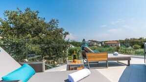 Una terraza en la azotea con sillones, una mesa y una botella de champán.