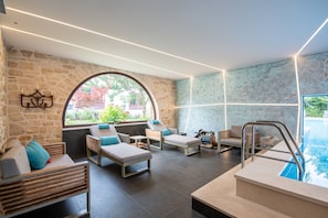 A modern spa area with a stone wall, a large arched window, and a pool. - Villa Elise with Pool (Novigrad)