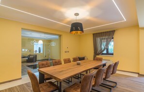 A conference room with a long wooden table and brown upholstered chairs, a modern pendant light, and a glass partition wall. - Villa Elise with Pool (Novigrad)