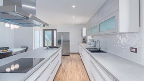 Una cocina moderna con armarios blancos, horno empotrado y refrigerador de acero inoxidable.