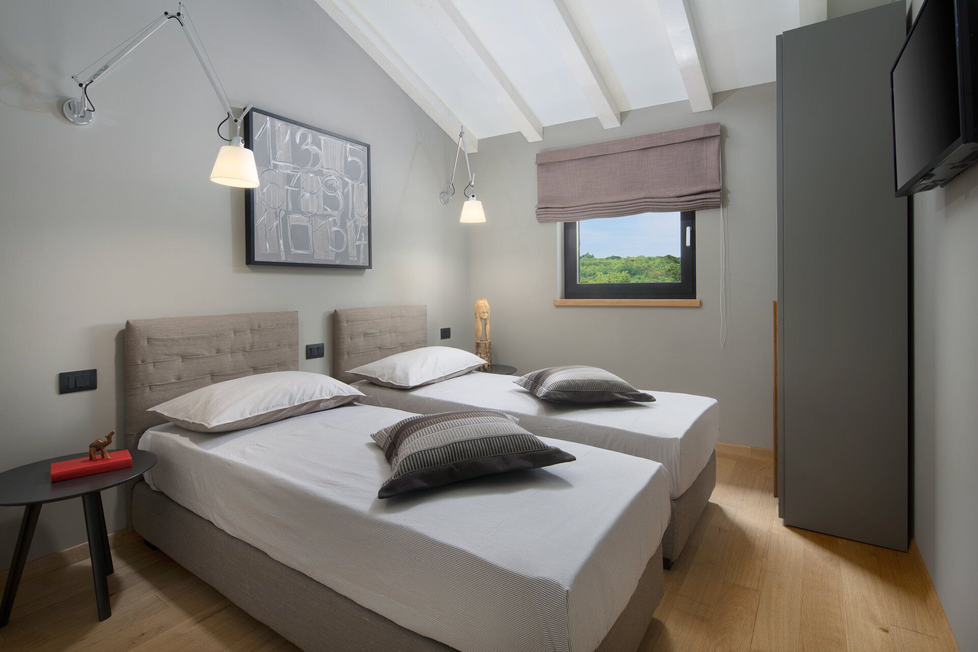 A modern bedroom with two beds, a large window with a view, a ceiling fan, and a flat-screen TV.
