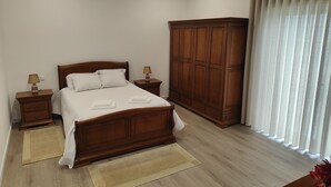 Una camera da letto con un letto in legno, due comodini con lampade, un armadio capiente e una finestra con tende.