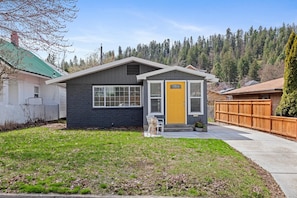 A two-story house with a grey exterior and a yellow front door.
