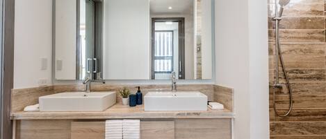 Ein modernes Badezimmer mit zwei Waschbecken, einem großen Spiegel und einer Dusche.
