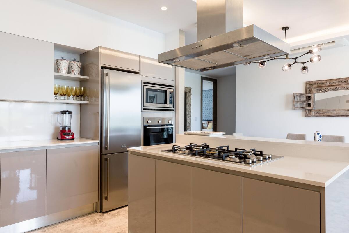 A modern kitchen with a central island, stainless steel appliances, and a built-in oven.