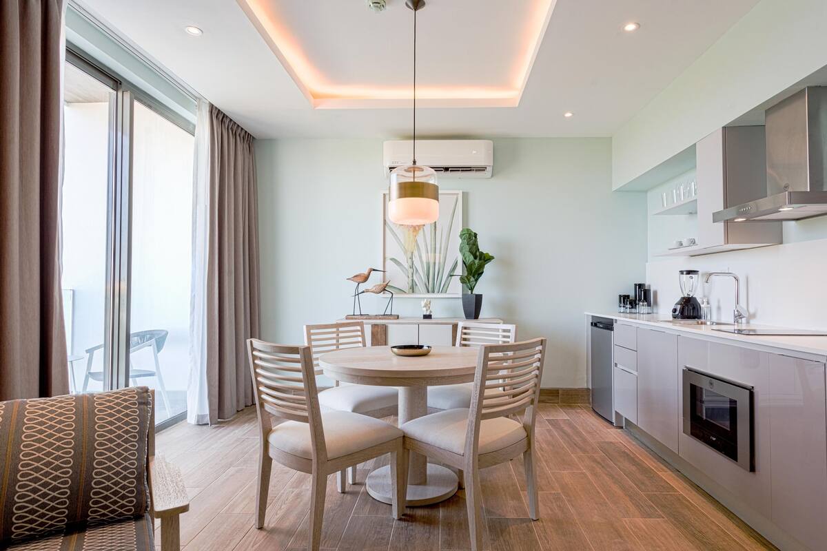 A modern kitchen with a dining area, featuring a round table, chairs, and a pendant light.