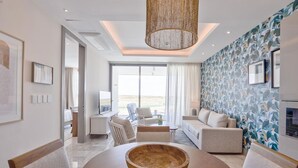 Una habitación de hotel moderna con un ventanal grande, una zona de comedor con mesa de madera y una pared con diseño.
